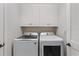 A laundry room with a white washer and dryer and overhead cabinets at 9547 Edgerton Dr. # 301, Myrtle Beach, SC 29572
