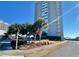 View of the South Hampton building with palm trees and manicured lawn against a blue sky at 9820 Queensway Blvd. # 303, Myrtle Beach, SC 29572