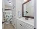 Well-lit bathroom with a single vanity, framed mirror, and a shower-tub combination with a palm tree curtain at 102-A N Poplar Dr., Surfside Beach, SC 29575