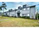 View of the two-story townhome with gray siding, trimmed shrubs and an expansive lawn at 10301 N Kings Hwy. # 15-8, Myrtle Beach, SC 29572