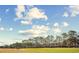 Beautiful landscape featuring manicured lawns, mature trees, and a clear blue sky with scattered clouds at 1043 Yellow Jasmine Dr., Longs, SC 29568