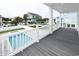 View of a pool and putting green from a covered porch with white railings and gray composite decking at 1211-B N Waccamaw Dr., Garden City Beach, SC 29576
