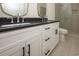 Modern bathroom featuring dual sinks with a black countertop, white cabinetry, and tiled shower at 1211-B N Waccamaw Dr., Garden City Beach, SC 29576