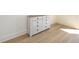 Bedroom featuring light wood flooring and a rustic white dresser with metal pulls against a white wall at 1211-B N Waccamaw Dr., Garden City Beach, SC 29576