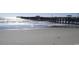 A long pier, partially shadowed by clouds, stretching into the ocean waves at 2017 Lone Cypress Dr, Myrtle Beach, SC 29579