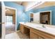 Bathroom with dual sinks, wood cabinets, and an adjacent bedroom and walk-in closet at 409 65Th Ave. N, Myrtle Beach, SC 29572