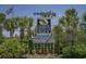 Welcome to North Myrtle Beach sign with palm trees, flowers, and the US flag in the background at 4719 S Ocean Blvd. # 209, North Myrtle Beach, SC 29582