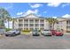 Exterior view of the condo building, featuring a parking lot and mature palm trees with blue skies at 4940 Windsor Green Way # 203, Myrtle Beach, SC 29579