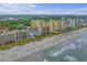 An aerial view shows a hotel along the shore, adjacent to a sandy beach filled with beachgoers enjoying the ocean view at 501 S Ocean Blvd. # 307, North Myrtle Beach, SC 29582
