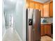 Kitchen featuring stainless steel refrigerator, wooden cabinetry, and adjacent hallway at 705 Beach Walk Pl. # 705, Myrtle Beach, SC 29577