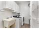 Bright laundry room with white cabinetry, a utility sink, and modern washer and dryer units at 898 Bluffview Dr., Myrtle Beach, SC 29579