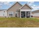 Tan home featuring a spacious, furnished screened-in porch and a well-manicured lawn in the backyard at 909 Witherbee Way, Little River, SC 29566