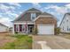 Charming two-story home featuring a mix of stone and siding, a two-car garage, and a well-manicured lawn at 909 Witherbee Way, Little River, SC 29566