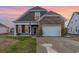 Charming two-story home featuring a stone accent wall, two car garage, and an American flag at 909 Witherbee Way, Little River, SC 29566