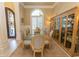 Elegant dining room with a large glass table, seating for ten, a decorative window, and a custom cabinet for storage at 9200 Bellasera Circle, Myrtle Beach, SC 29579