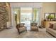 Comfortable sitting area with stone accent wall and sliding glass doors to patio at 9200 Bellasera Circle, Myrtle Beach, SC 29579