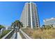 A tall modern building with multiple balconies overlooks a sandy path leading to the beach at 9820 Queensway Blvd. # 109, Myrtle Beach, SC 29572