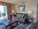 Comfortable living room features a plush sofa, accent pillows, and a sliding glass door to a balcony at 9820 Queensway Blvd. # 109, Myrtle Beach, SC 29572