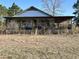 A quaint home featuring a covered porch enclosed by lattice, showcasing weathered charm and overgrown foliage at 1264 Harrelson Dr., Longs, SC 29568