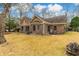 Backyard of home featuring a brick exterior, brown grass, and multiple trees with a blue rain barrel on the side of the house at 20 Brassie Dr., Carolina Shores, NC 28467