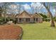 Brick home with a lush green lawn, surrounded by mature trees, offering a serene outdoor space at 20 Brassie Dr., Carolina Shores, NC 28467