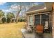 Cozy patio area with outdoor seating, part of a spacious backyard with lush grass and mature trees, perfect for relaxing at 20 Brassie Dr., Carolina Shores, NC 28467