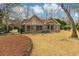 Backyard of home featuring a brick exterior, brown grass, and multiple trees with a blue rain barrel on the side of the house at 20 Brassie Dr., Carolina Shores, NC 28467