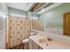 Bathroom features a cream-colored vanity and sink, matching toilet, shower with a palm tree curtain, and a large mirror at 20 Brassie Dr., Carolina Shores, NC 28467