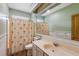 Bright bathroom with a large mirror, vanity, toilet, and a shower with a palm tree-themed curtain at 20 Brassie Dr., Carolina Shores, NC 28467