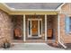Cozy front porch with brick columns, seating, and a decorative front door, creating a welcoming entrance at 20 Brassie Dr., Carolina Shores, NC 28467