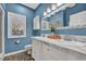 Stylish blue bathroom with a double vanity, marble countertop, and a decorative wall mirror at 435 Ocean Creek Dr. # 2705, Myrtle Beach, SC 29572