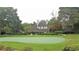 Beautifully landscaped putting green with red flags, surrounded by mature trees and well-kept gardens at 435 Ocean Creek Dr. # 2705, Myrtle Beach, SC 29572