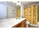 Bathroom featuring a wide mirror, white countertop, wooden cabinets, and a palm-themed shower curtain over the tub at 6095 Catalina Dr. # 1614, North Myrtle Beach, SC 29582