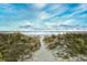 Sandy path through dunes leading to the ocean's edge and blue sky at 6095 Catalina Dr. # 1614, North Myrtle Beach, SC 29582