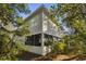 Landscaped view of the rear exterior of the home featuring mature trees and a screened porch at 98 Wallys Way # 1, Pawleys Island, SC 29585