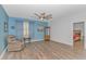 Comfortable living room featuring wood floors, a ceiling fan, cozy seating, and bright blue walls at 1119 Maxwell Dr., Little River, SC 29566