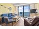 Cozy living room features a blue sofa and a sliding glass door with balcony overlooking the ocean at 1210 N Waccamaw Dr. # 1507, Murrells Inlet, SC 29576