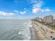 Expansive aerial view of the beach with blue skies and ocean, showcasing beachfront buildings at 1501 Ocean Blvd. S # 607, Myrtle Beach, SC 29577