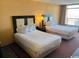 Cozy bedroom featuring two beds, lamps, and a view from the balcony at 1501 S Ocean Blvd. # 1203, Myrtle Beach, SC 29577
