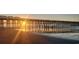 Beach view featuring the sun setting behind a pier with golden light reflecting off wet sand, and people visible at 217 N Myrtle St. # 1, Myrtle Beach, SC 29577