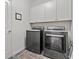 Well-lit laundry room with modern, dark gray appliances and ample upper cabinet space at 236 Craigflower Ct., Longs, SC 29568