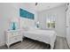 Bright bedroom with hardwood flooring, shuttered window, ocean wave decor, and sleek white furniture at 2406 Seabreeze Pl., Myrtle Beach, SC 29577