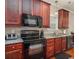 Close-up view of a kitchen featuring cherry wood cabinets, granite counters, and black appliances at 337 Sailors Ct., Myrtle Beach, SC 29577