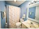 Bright blue bathroom offering a shower with patterned curtain, white vanity, and decorative seashell accents at 4430 Eastport Blvd. # L9, Little River, SC 29566