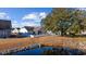 Large backyard with a pond, white fence, well-maintained grass, patio, and lush foliage at 509 Hillsborough Dr., Conway, SC 29526