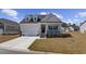 Charming home featuring a welcoming front porch, attached garage, and well-manicured lawn on a sunny day at 517 Antebellum Ln., Georgetown, SC 29440