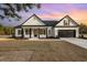 Charming white farmhouse with black accents, inviting front porch, and two-car garage at sunset at 1052 Merritt Rd, Conway, SC 29526