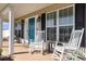 Cozy front porch features rocking chairs, bright blue door, and ample natural light streaming through the windows at 115 Blue Pride Dr., Loris, SC 29569