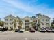 Well-maintained three-story building with palm trees and ample parking under a blue sky at 601 Hillside Dr. N # 4535, North Myrtle Beach, SC 29582