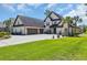Beautiful home with a lush green lawn, manicured garden beds, and a spacious concrete driveway and three car garage at 9785 Anchor Dr., Longs, SC 29568
